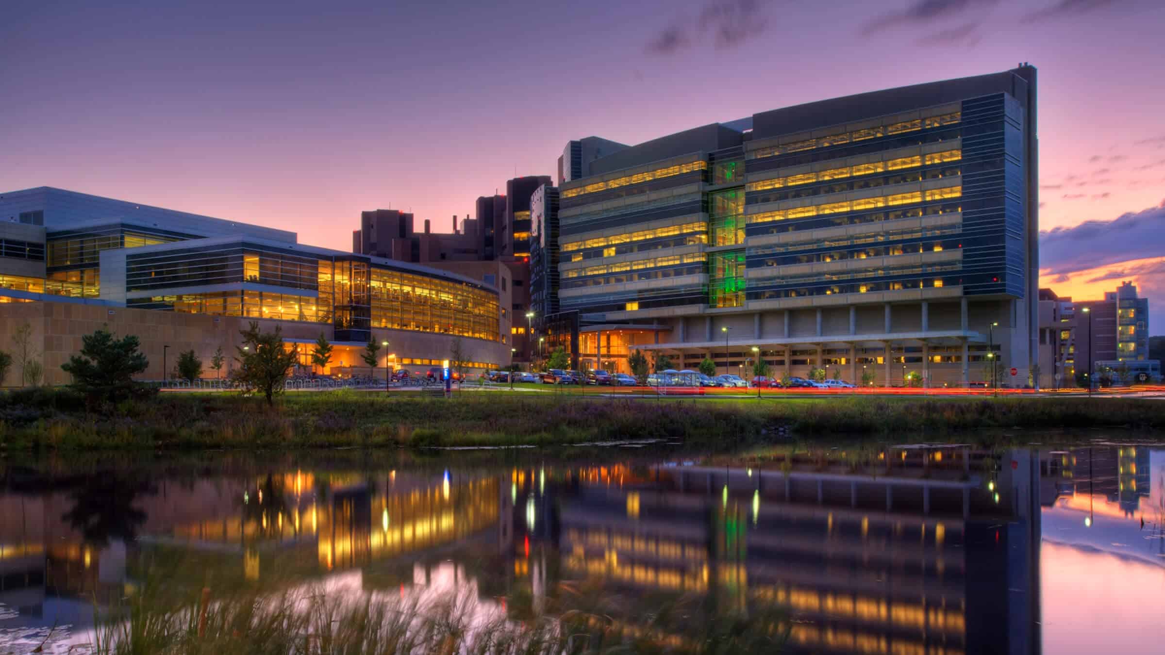 Wisconsin Institutes for Medical Research - Exterior View of Building from Lake, Lit at Dusk